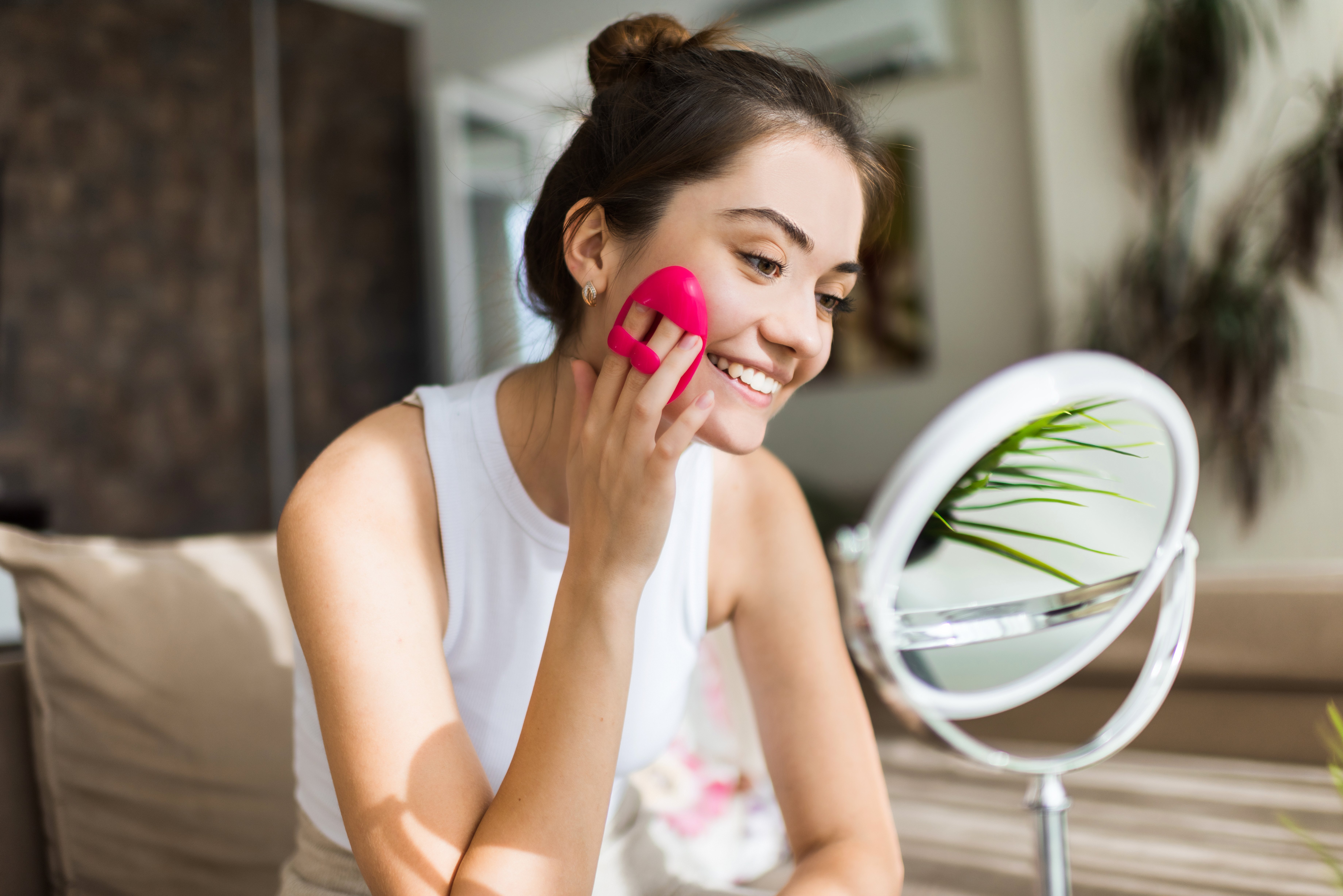young-caucasian-smiling-woman-is-doing-facial-massage-looking-mirror